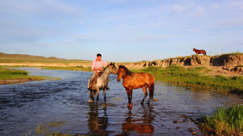 A Kazakhstan man sits on his horse in the river.