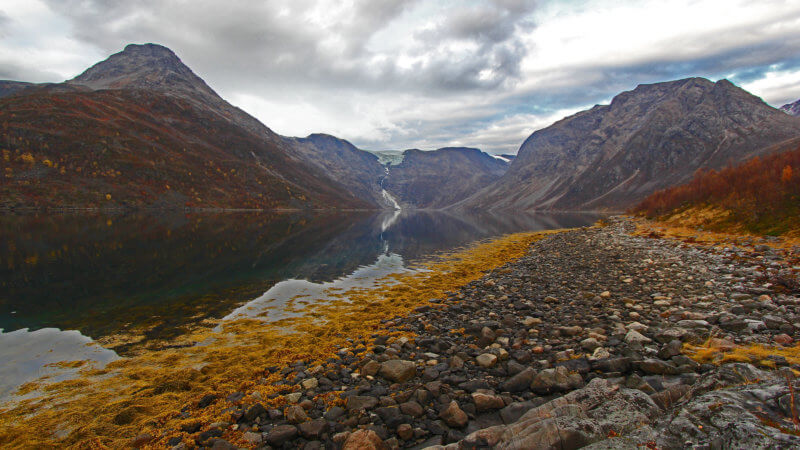 A quiet and isolated Norwegian fjord with a hanging valley and glacier in the distance.
