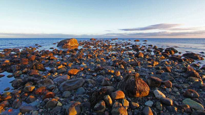 A line of boulders on a tidal shoreline extend out into the Barents Sea.