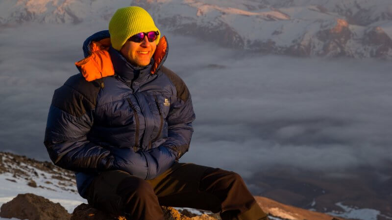 Chris, a British skier, pictured smiling into the sunset outside of an Iranian mountain hut.