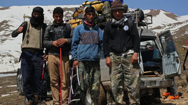 A group of Afghan porters stood in front of a 4x4 vehicle on the approach road to Mt. Damavand in Iran.