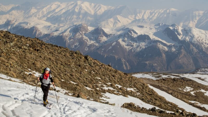 Shirin Shabestari, on the left of the image, skiing up Mt. Damavand on a sunny day. The snowy Alborz Mountains is in the background.