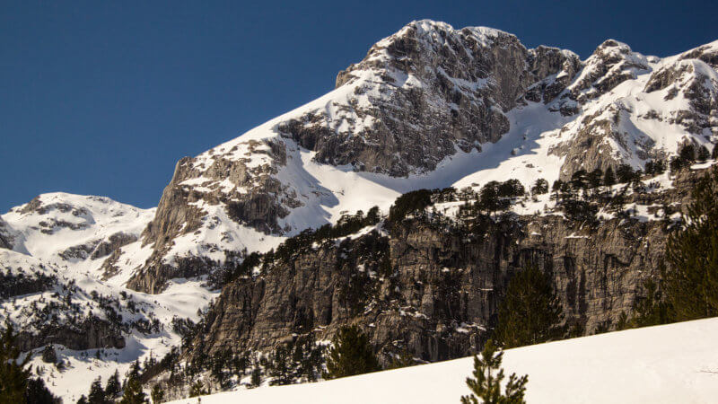 A rocky escarpment beneath a large alpine mountain in Montenegro.