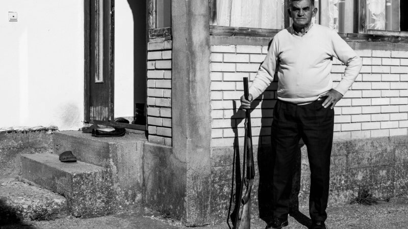 Black and white image of Montenegro man posing with his shotgun.