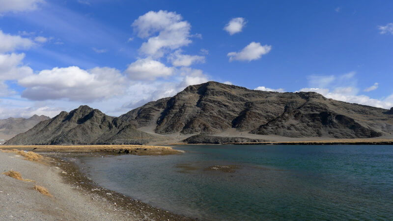 Khovd River, Western Mongolia on a sunny day with a mountain in the distance.