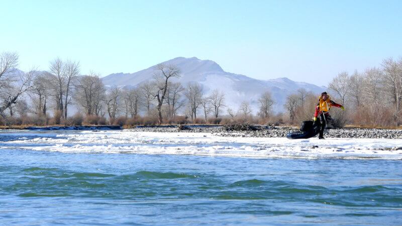A far shot of Jamie towing his packraft on a frozen stretch of the Khovd River in Mongolia.
