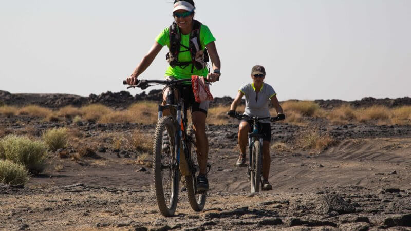 Two women on mountain bikes riding up Erta Ale in Ethiopia.